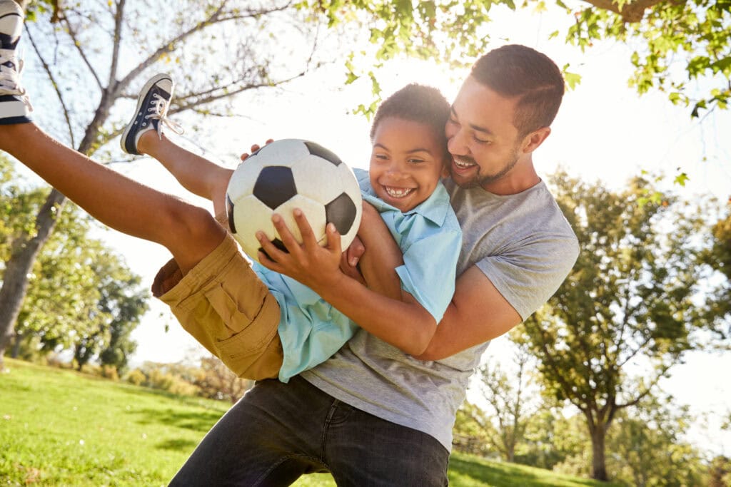 father and son playing soccer outside